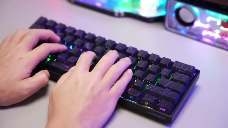 Hands typing on RGB mechanical keyboard with customizable lighting effects on a modern desktop setup