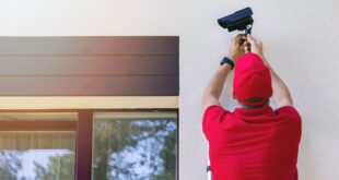 technician installing outdoor security surveillance camera on house exterior wall