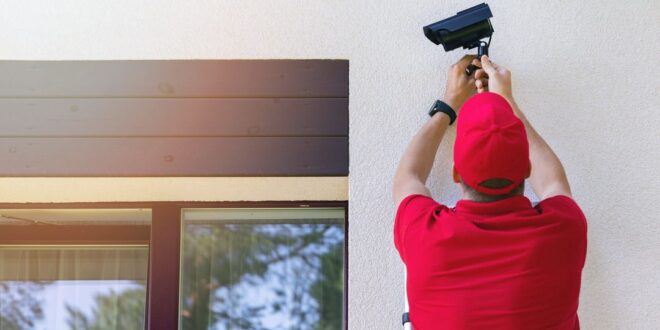 technician installing outdoor security surveillance camera on house exterior wall