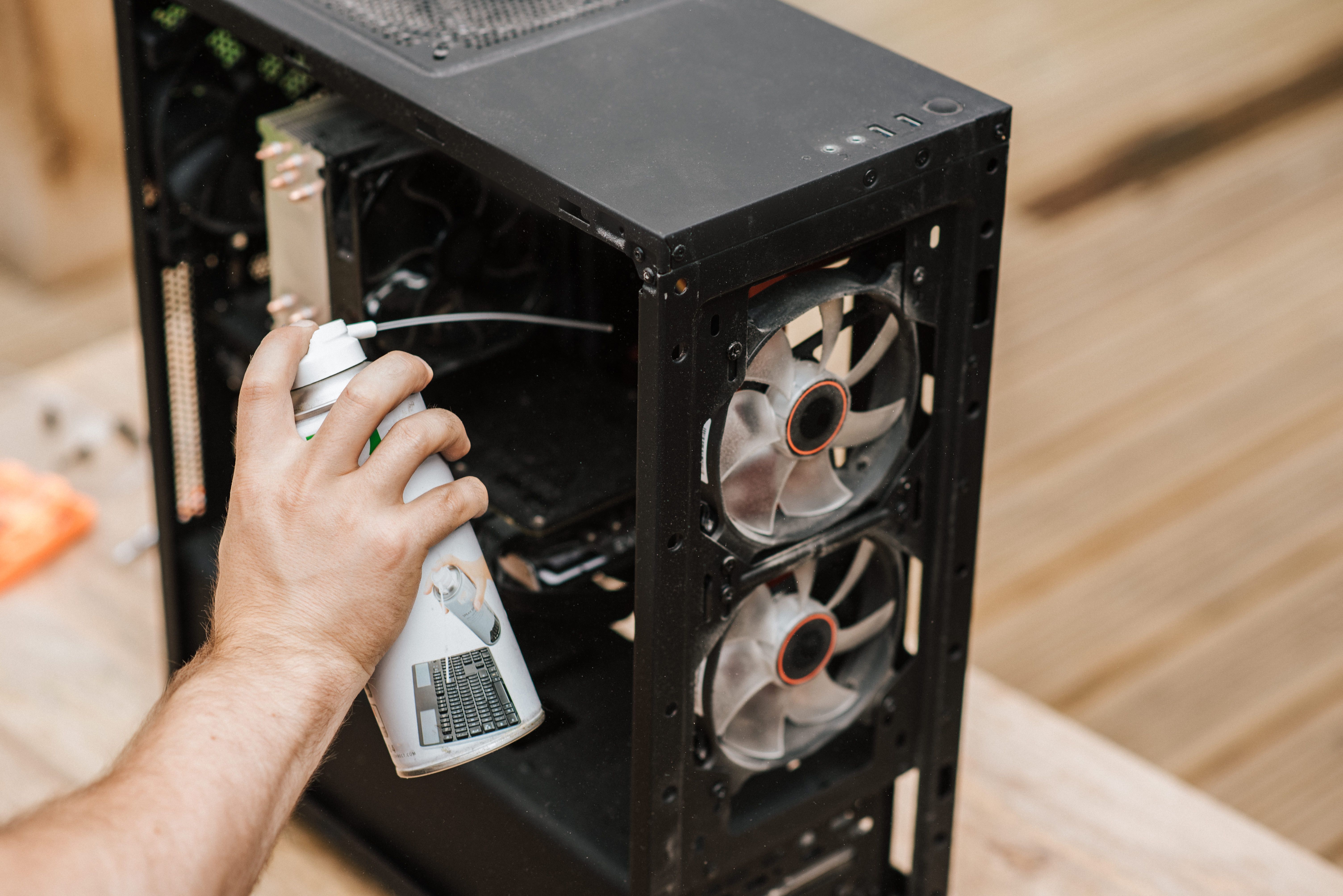 Technician cleaning dust from computer hardware, illustrating maintenance that can help prevent heat-related slowdowns.