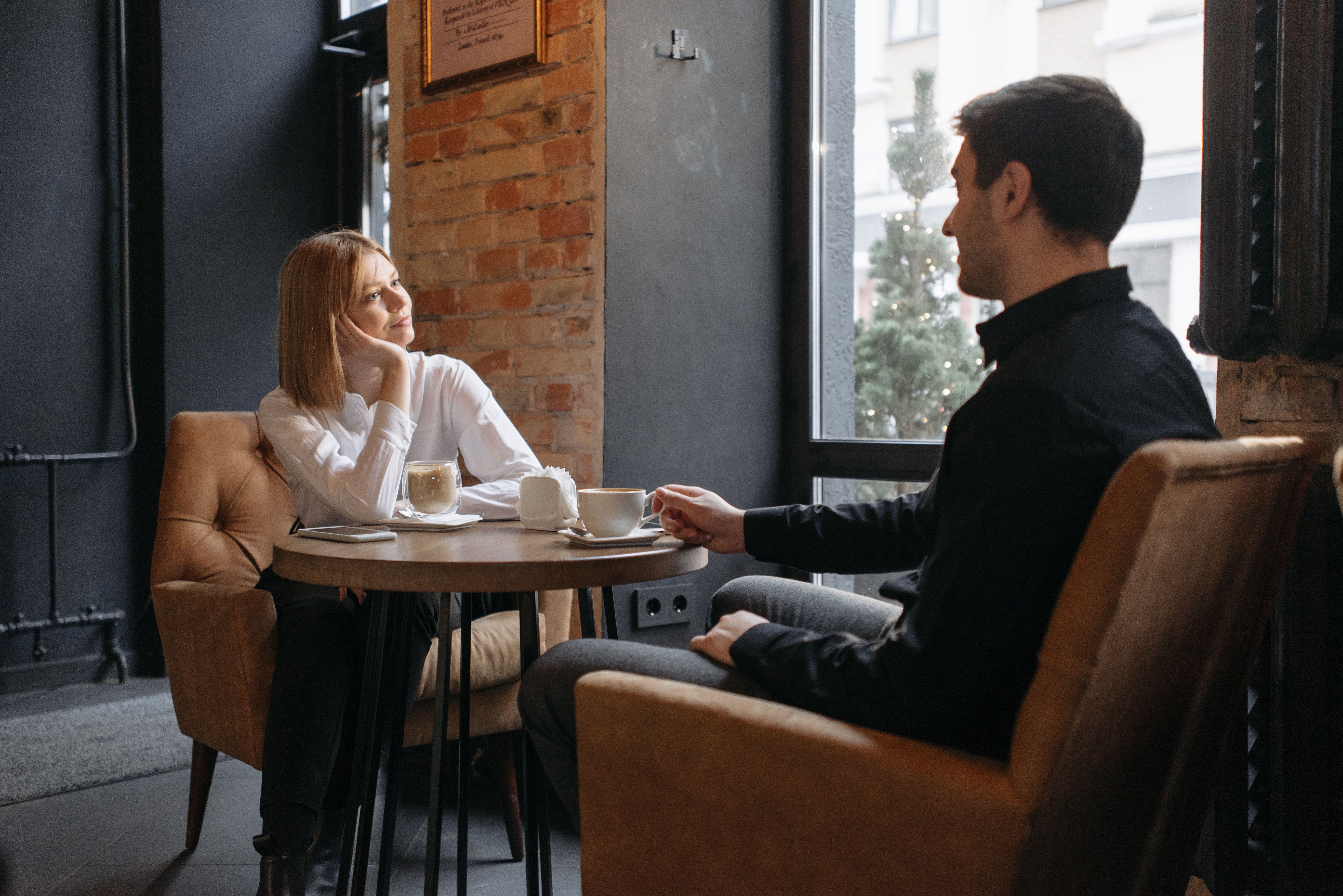 A couple having coffee and talking by a cafe window, a candid scene of modern dating.