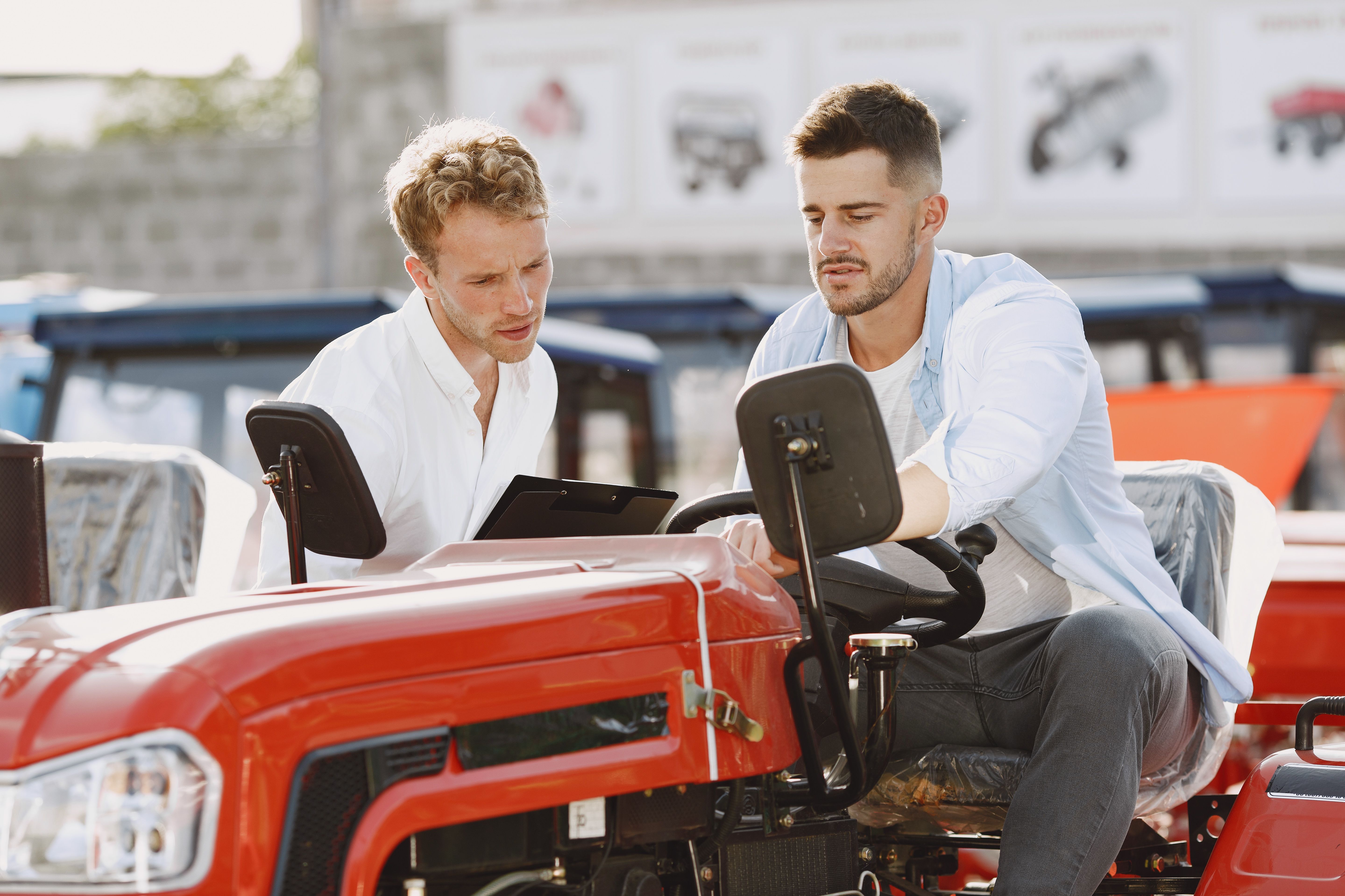 Two men evaluate a red tractor at an outdoor dealership, representing a new equipment purchase.