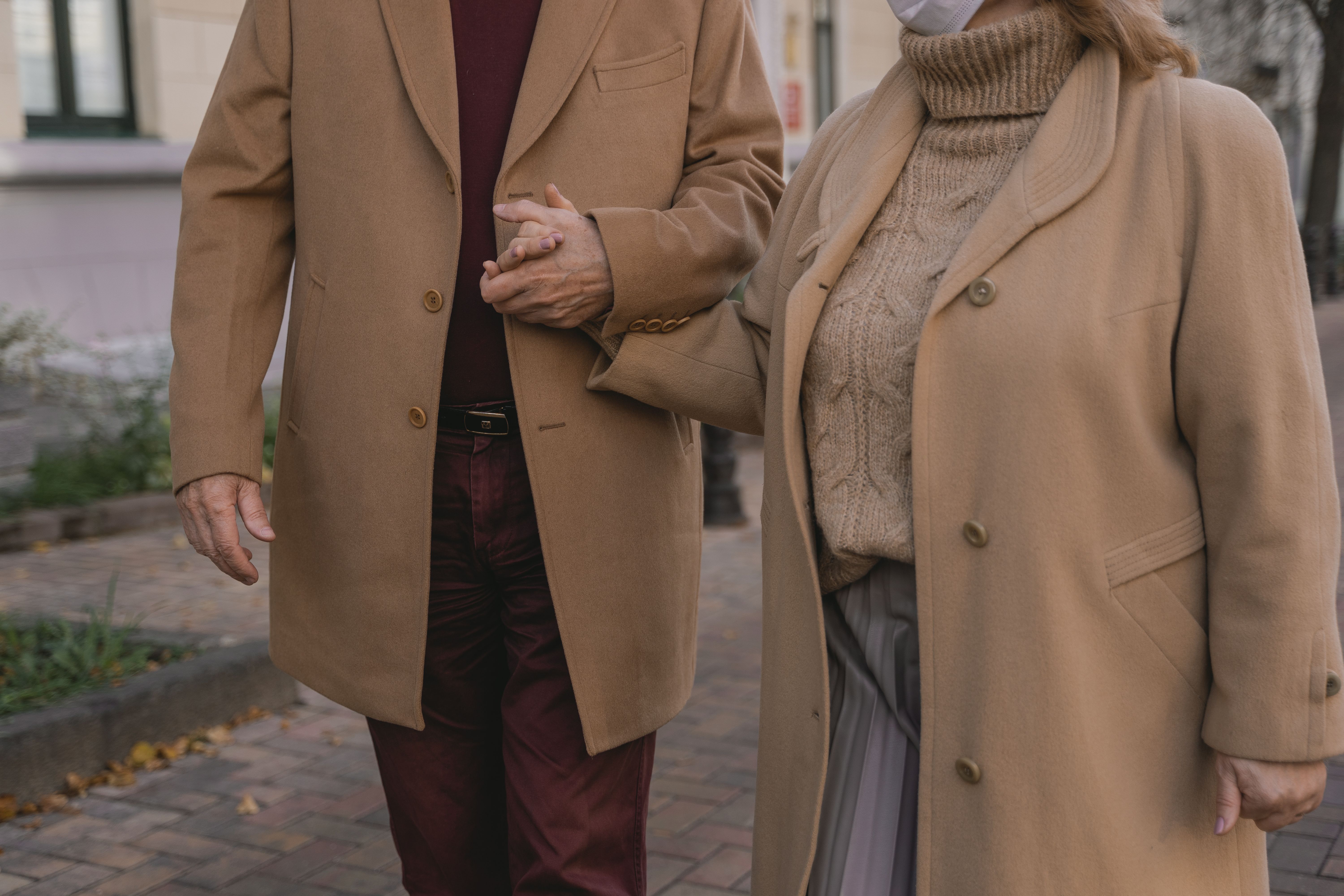 Older couple holding hands during an autumn walk, showing companionship in later-life relationships.
