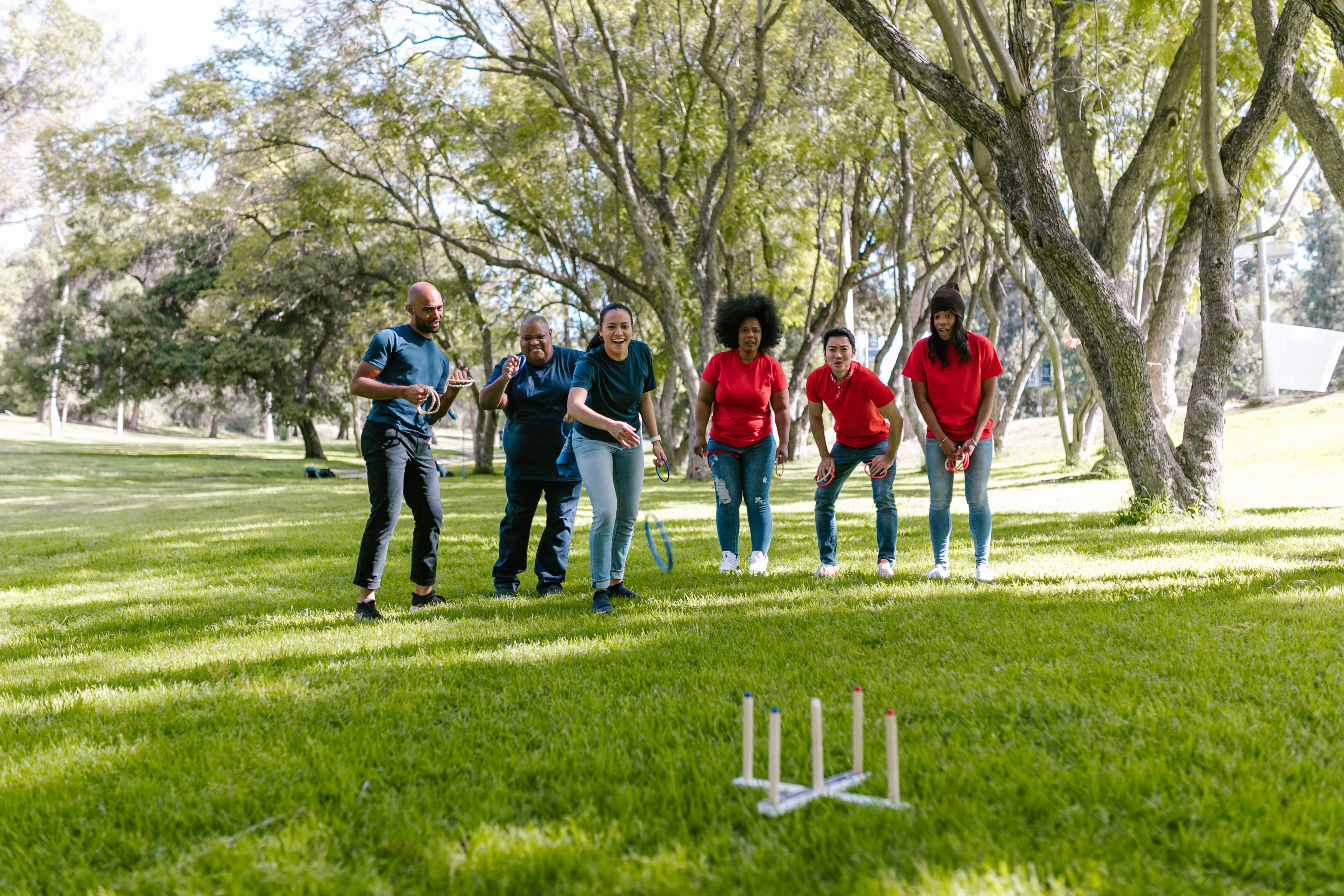 Coworkers play ring toss together outdoors, showing a relaxed, low-pressure team-building activity.