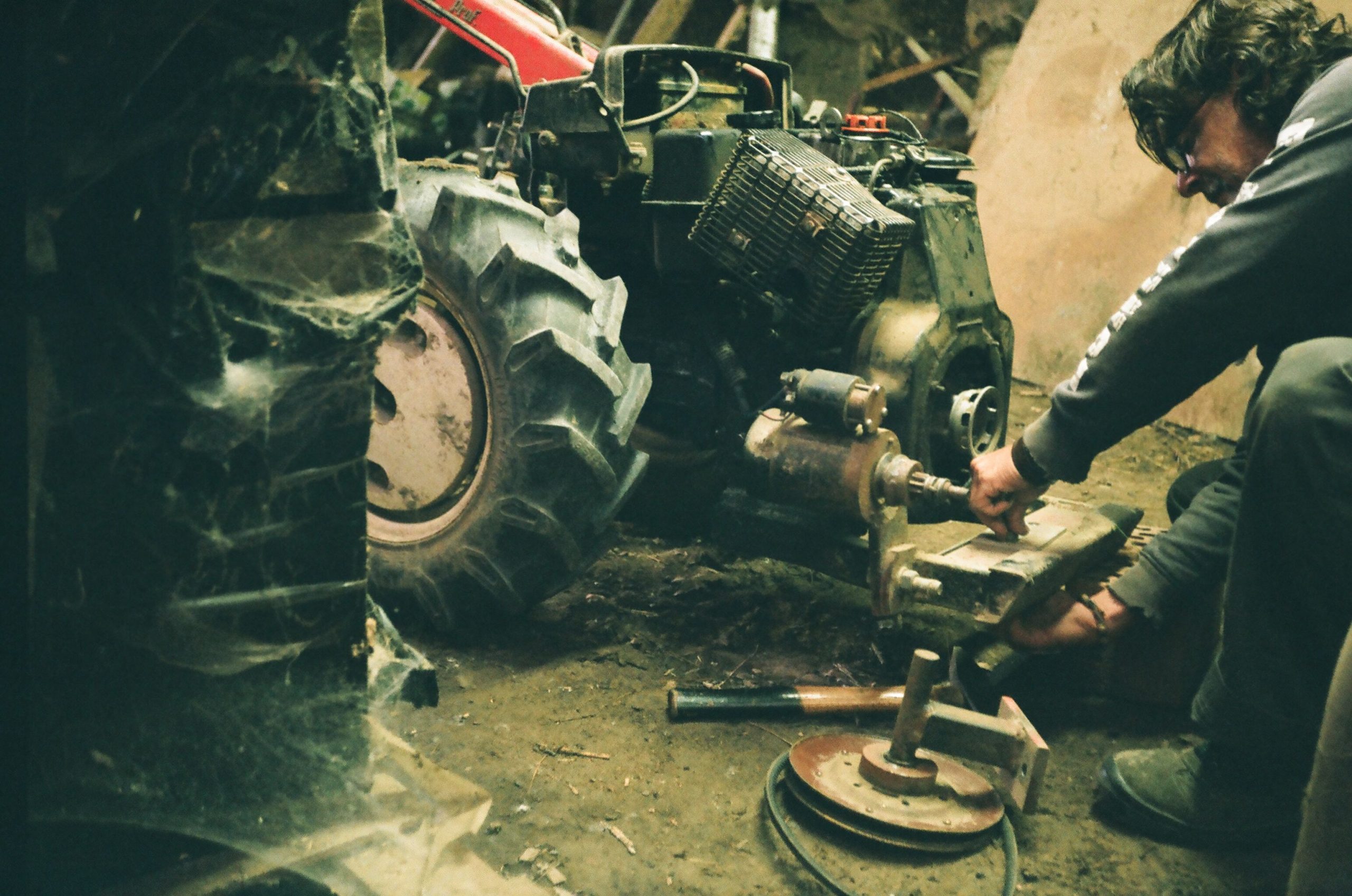 Mechanic inspecting a tractor engine during an agricultural machinery repair.