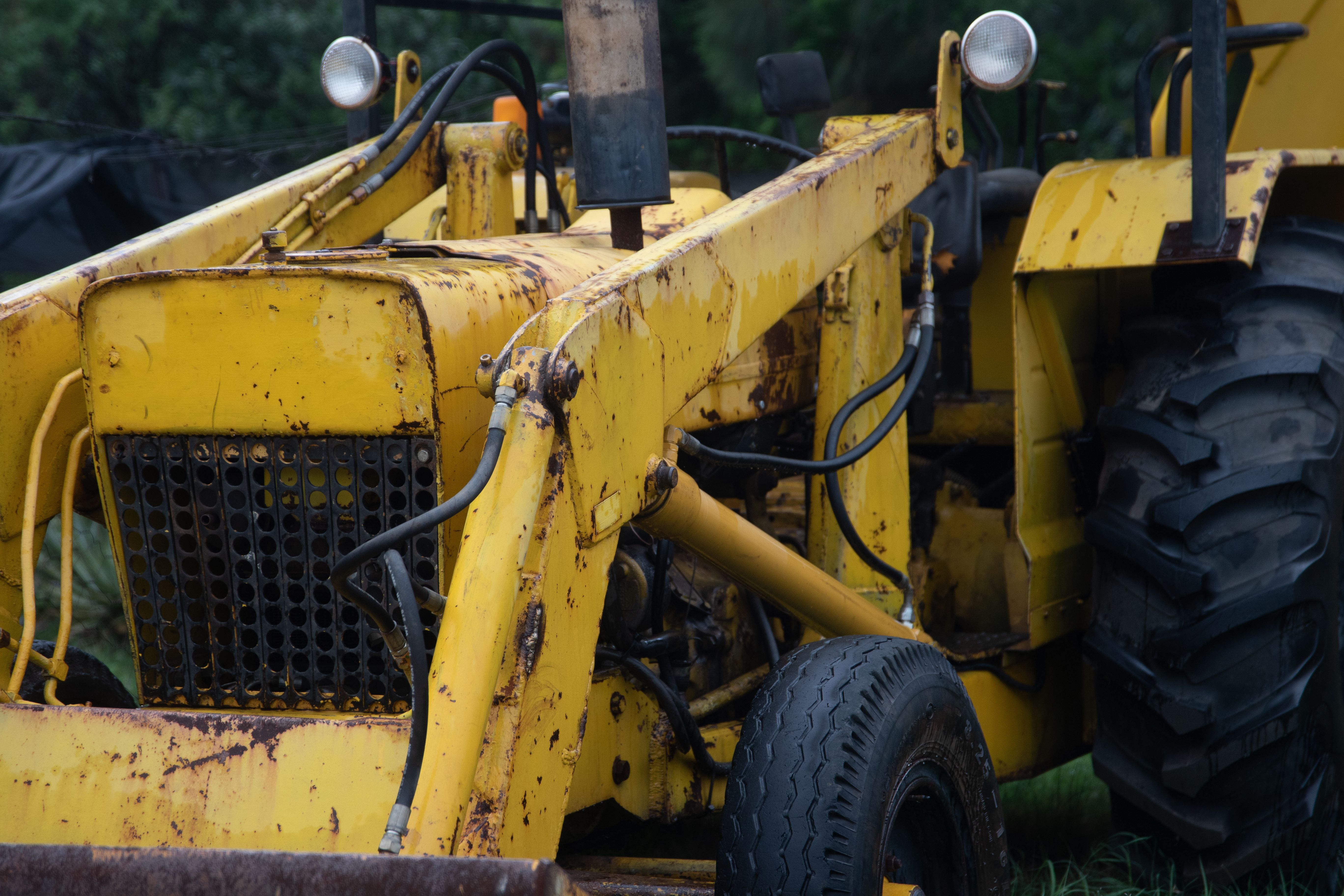Close view of a weathered yellow tractor showing signs of age and use.